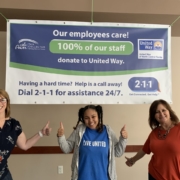 Three Tax Collector Employees standing under United Way banner.