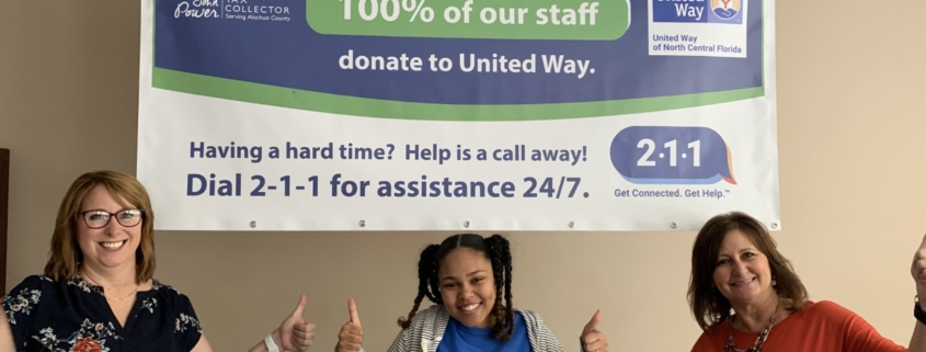 Three Tax Collector Employees standing under United Way banner.